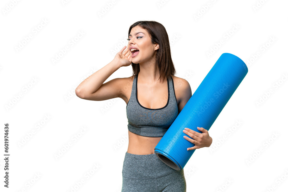 Young sport woman going to yoga classes while holding a mat over isolated chroma key background listening to something by putting hand on the ear Young sport woman going to yoga classes while holding a mat over isolated chroma key background listening to something by putting hand on the ear