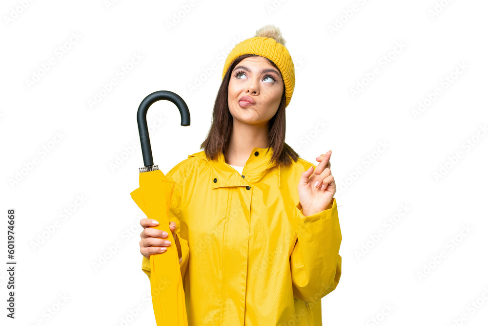 Young Russian woman with rainproof coat and umbrella over isolated chroma key background with fingers crossing and wishing the best Young Russian woman with rainproof coat and umbrella over isolated chroma key background with fingers crossing and wishing the best