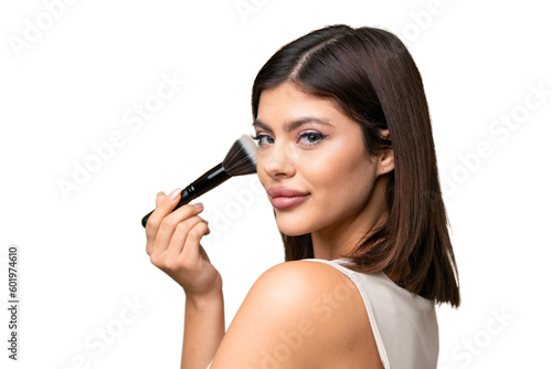 Young Russian woman with rainproof coat and umbrella over isolated chroma key background holding makeup brush