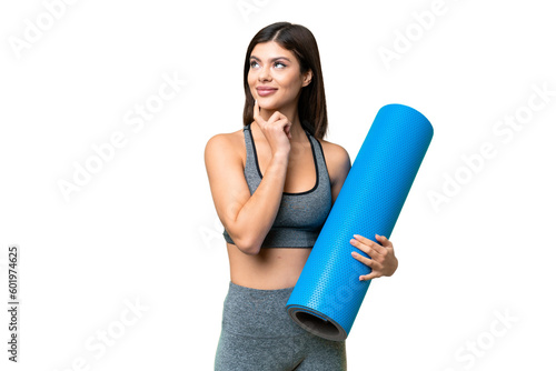 Fototapeta Naklejka Na Ścianę i Meble -  Young sport woman going to yoga classes while holding a mat over isolated chroma key background thinking an idea while looking up
