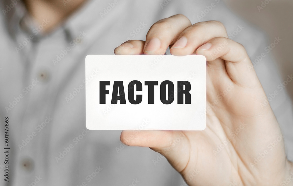 Card with text Factor in a man's hand Card with text Factor in a man's hand