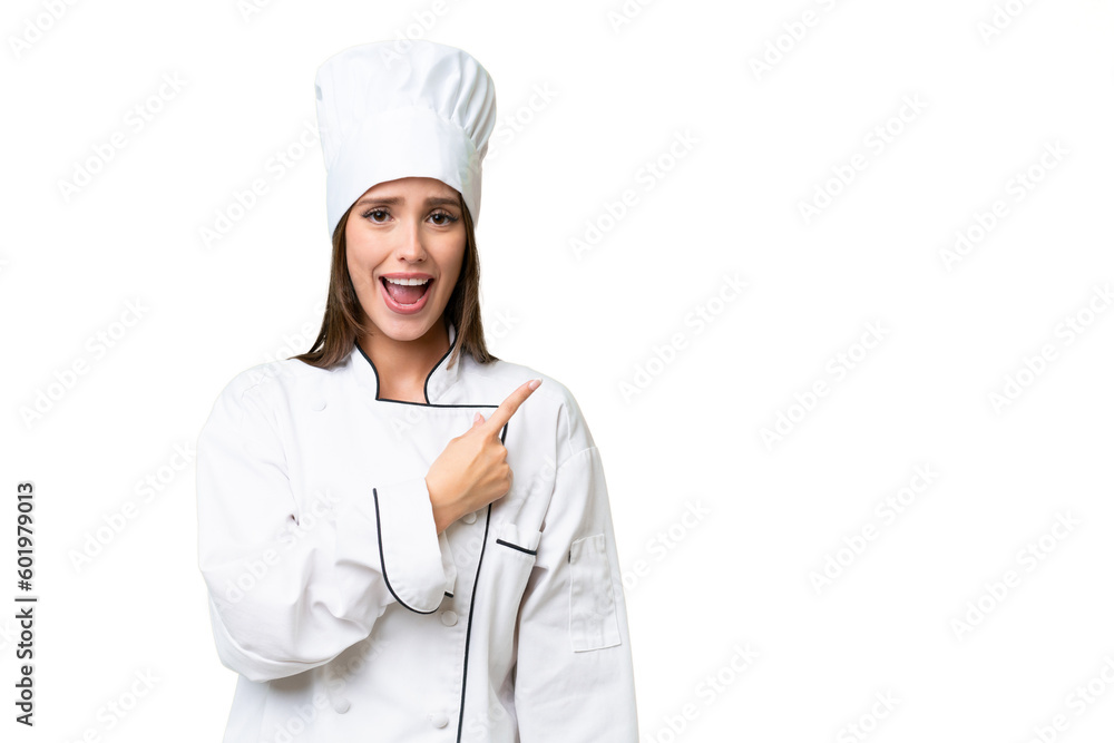 Young chef caucasian woman over isolated background surprised and pointing side Young chef caucasian woman over isolated background surprised and pointing side