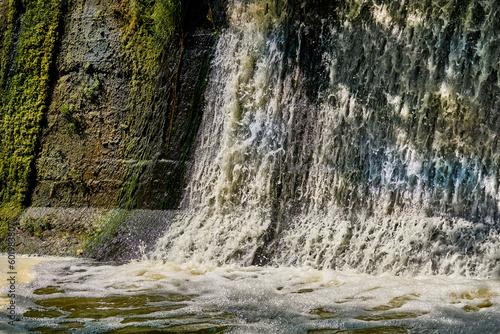 Pleasant freshness.River dam with clear flowing water on a warm sunny day