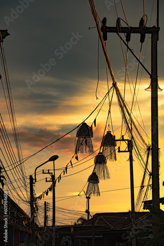 Silhouette of electrical mast and cables, woven fish baskets, and decorative flags, with golden sky.