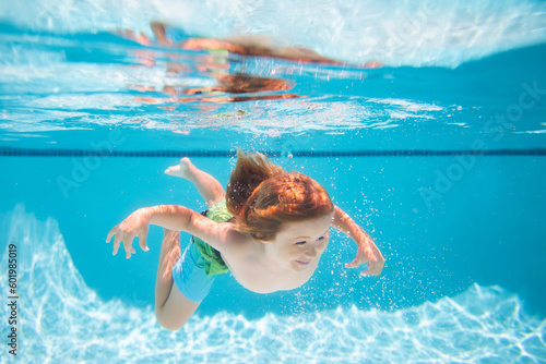 Young boy swim and dive underwater. Under water portrait in swim pool. Child boy diving into a swimming pool. Summer kids activity, watersports. © Volodymyr