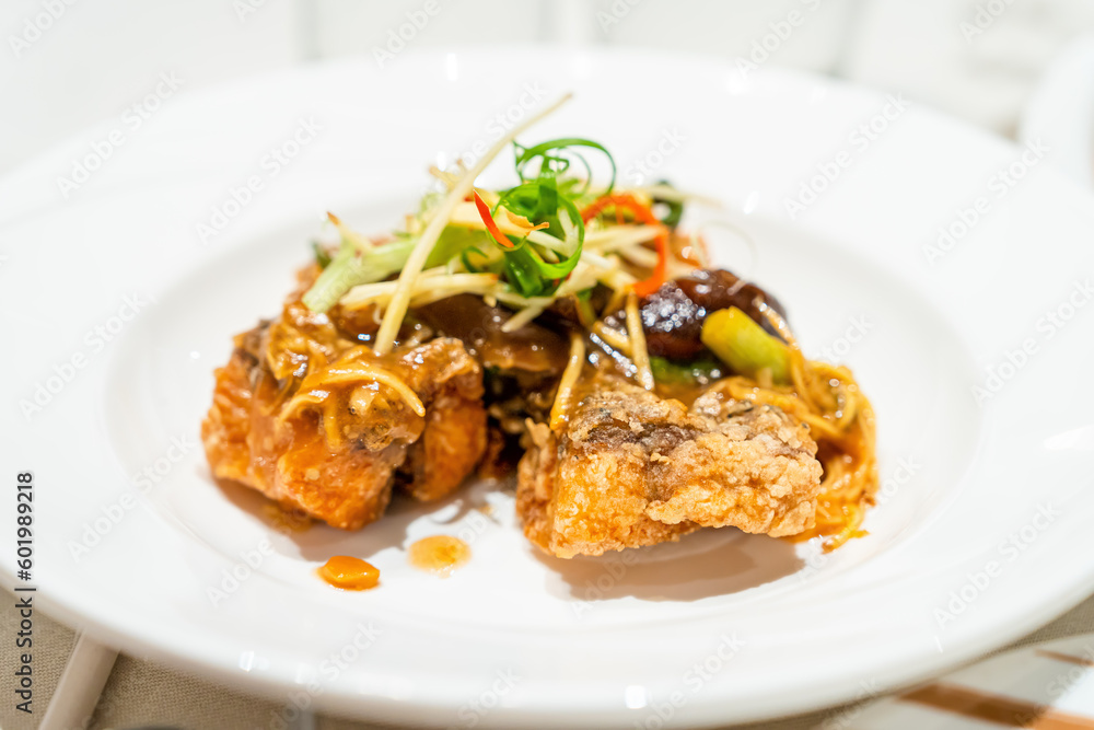 Crispy Fish with Ginger topped with chili sauce Placed on a white plate looks appetizing. in a Thai restaurant