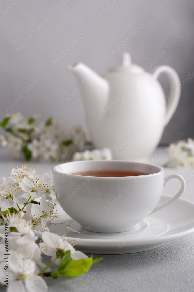 A cup of tea on the table with spring cherry blossoming branches A cup of tea on the table with spring cherry blossoming branches