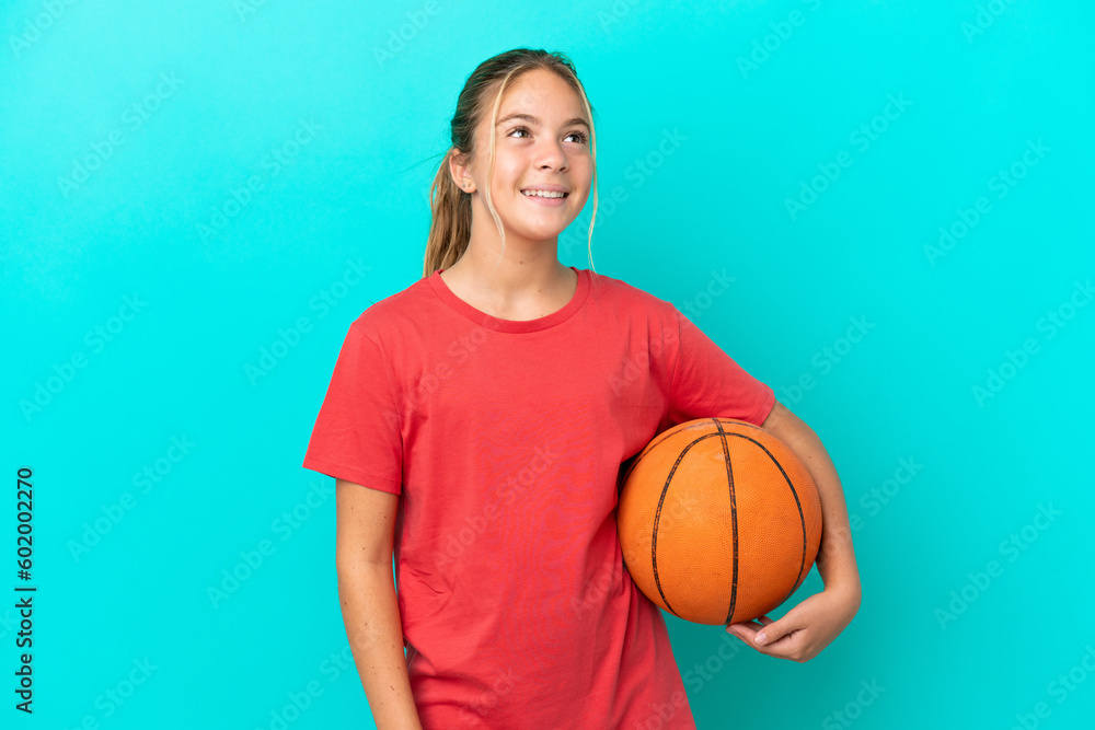 Little caucasian girl playing basketball isolated on blue background thinking an idea while looking up