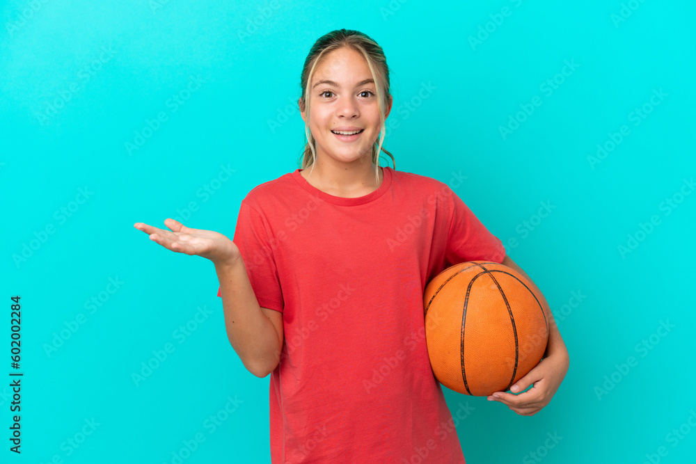 Little caucasian girl playing basketball isolated on blue background with shocked facial expression