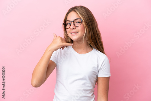 Little caucasian girl isolated on pink background With glasses and doing phone gesture
