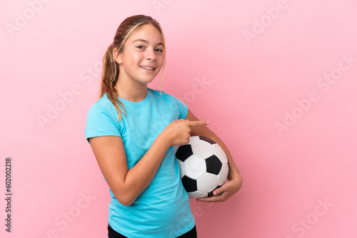 Little football player girl isolated on pink background pointing finger to the side © luismolinero
