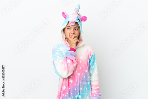 Little girl with unicorn pajamas isolated on white background having doubts and with confuse face expression
