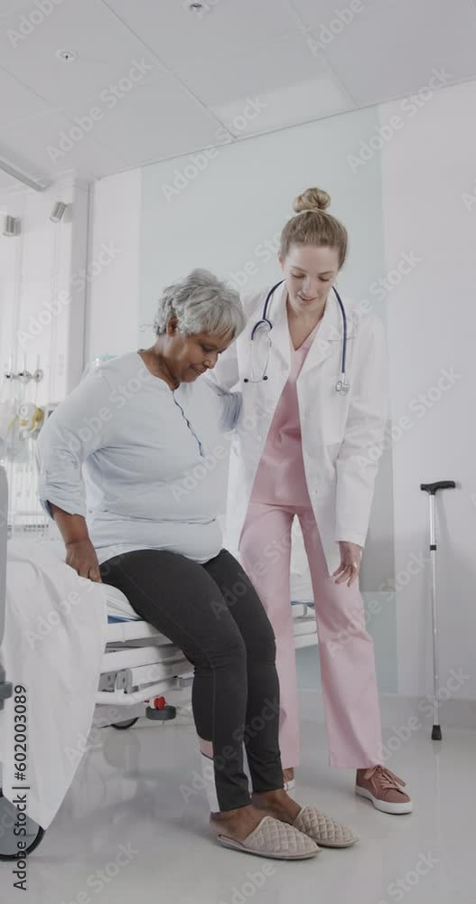 Vertical video of diverse female doctor helping senior female stand from bed, slow motion Vertical video of diverse female doctor helping senior female stand from bed, slow motion
