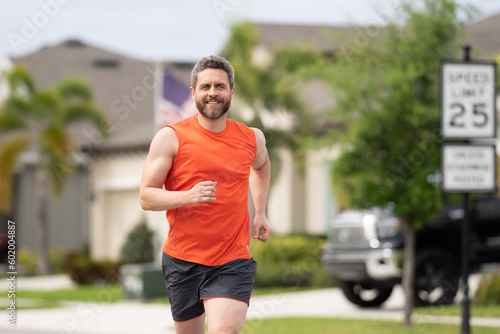Handsome middle aged man running across american neighborhood. Athletic man running outdoor. Healthy lifestyle. Active healthy runner jogging outdoor.