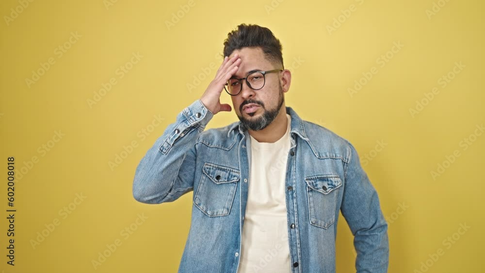 Young latin man stressed standing over isolated yellow background Young latin man stressed standing over isolated yellow background