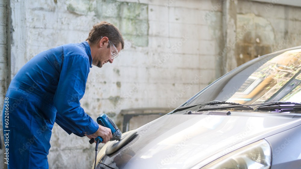 Caucasian man is using car polishing machine in repair mechanic painting shop
