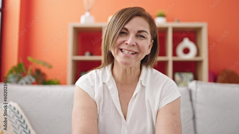 Middle age hispanic woman sitting on sofa speaking at home Middle age hispanic woman sitting on sofa speaking at home
