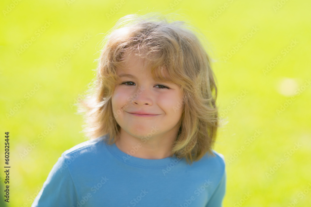 Lifestyle portrait of cute kid outdoors. Summer kids outdoor portrait. Close-up face child playing outdoors in summer park. Cute funny blonde little child close up portrait on green grass background. Lifestyle portrait of cute kid outdoors. Summer kids outdoor portrait. Close-up face child playing outdoors in summer park. Cute funny blonde little child close up portrait on green grass background.