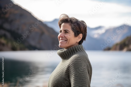 Portrait of a smiling middle-aged woman standing by a lake in the mountains