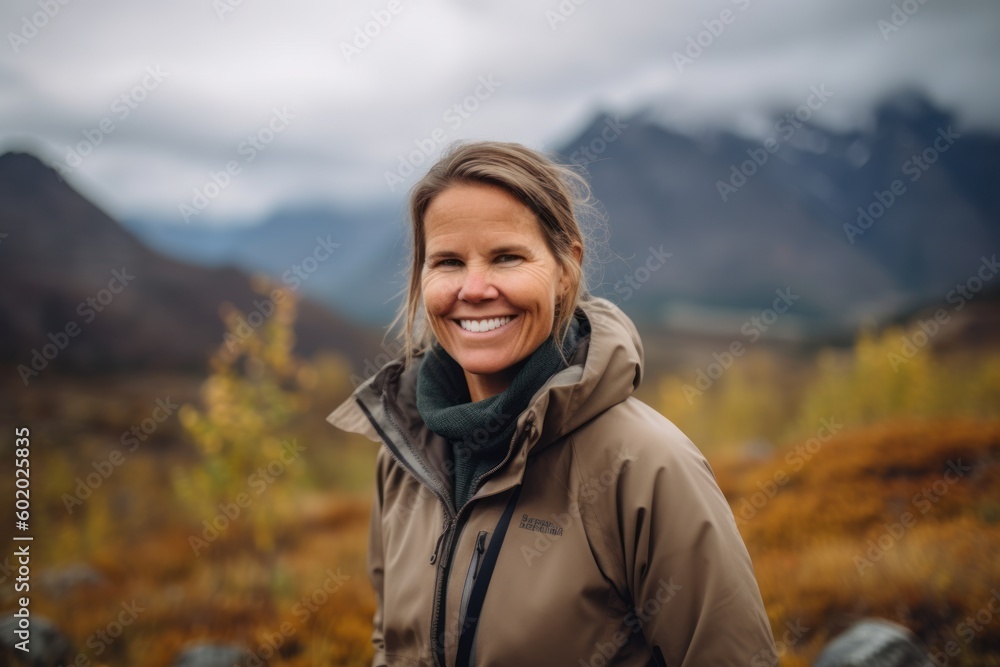 Mature woman hiker smiling at camera in autumn mountain landscape.