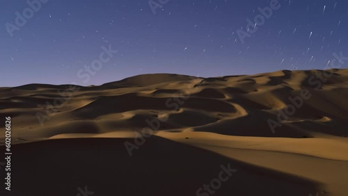 Beautiful dramatic night time lapse over the desert sand dune with moonlight shadow of Abu Dhabi, UAE photo