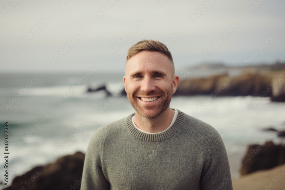 Portrait of handsome man smiling at camera while standing on the beach Portrait of handsome man smiling at camera while standing on the beach