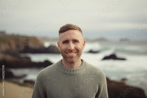 Portrait of handsome man smiling at camera at the beach in summer