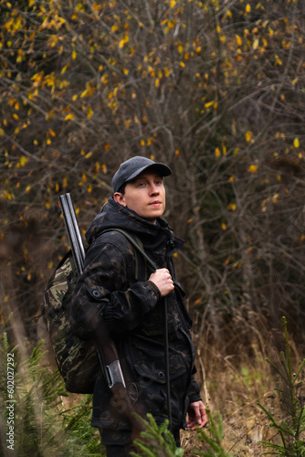 Hunter with a gun and a backpack in the forest.