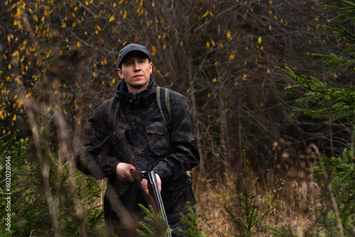 Hunter with a gun and a backpack in the forest.