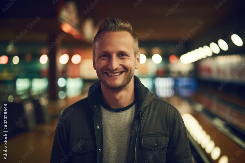 Portrait of young man standing in bowling alley at night, looking at camera.
