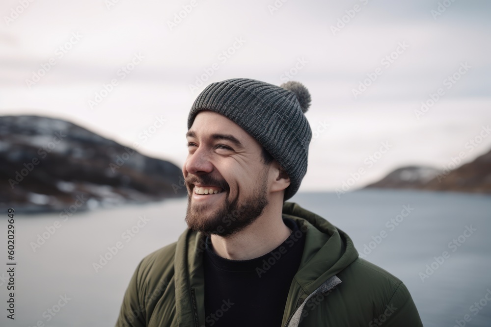 Portrait of a smiling man in a hat and green jacket on a background of the sea. Portrait of a smiling man in a hat and green jacket on a background of the sea.