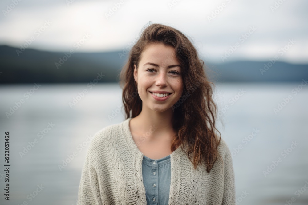 Portrait of a beautiful young woman with long brown hair in a knitted sweater on the background of the lake. Portrait of a beautiful young woman with long brown hair in a knitted sweater on the background of the lake.