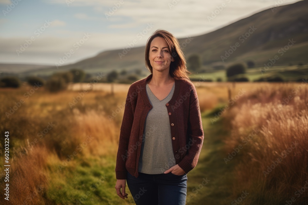 Beautiful young woman standing in a field with her arms akimbo Beautiful young woman standing in a field with her arms akimbo