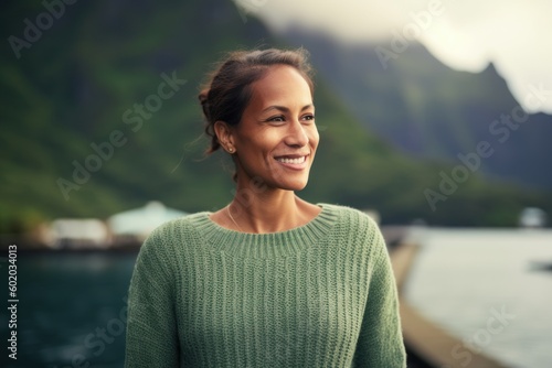 Portrait of a smiling woman in a green sweater on the background of mountains