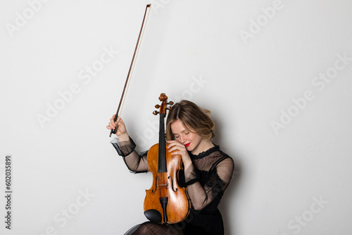 Young elegant blonde girl playing a violin. Portrait of a female violinist. Isolated on white background.