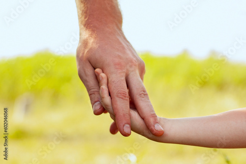 Two hands of an adult and a child. A father leads his little son by the hand, summer outdoor. Trust, help, care, parenthood, childhood concept