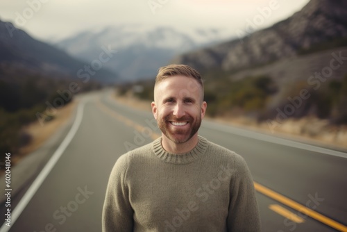 Portrait of smiling man standing on road in the middle of the mountains © Robert MEYNER