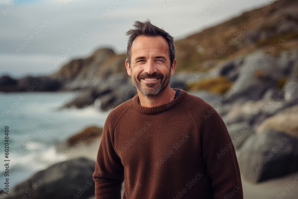 Portrait of a handsome man smiling at the camera while standing on the beach