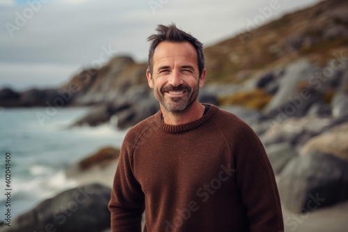 Portrait of a handsome man smiling at the camera while standing on the beach