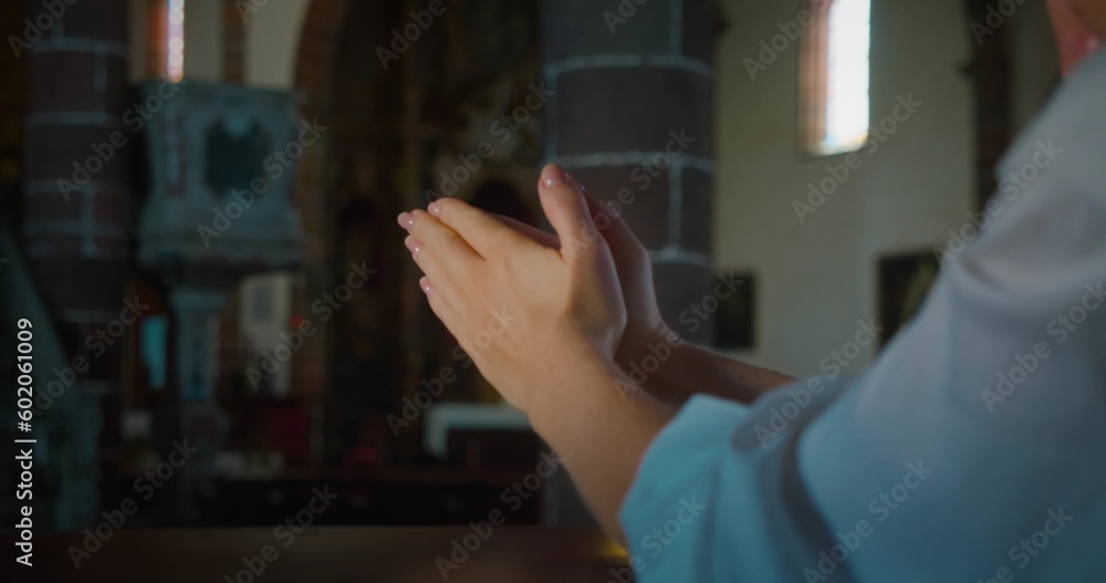 Christian woman folded hands in prayer inside a church. Religious faith in power of Christ the Redeemer and Gods love.