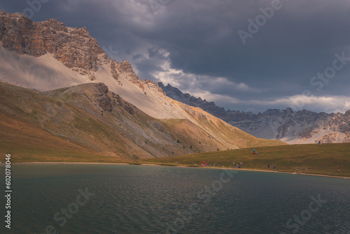 People resting around the mountain lake Lac de Soulier in the Queyras valley in the Alps (Hautes-Alpes, France)