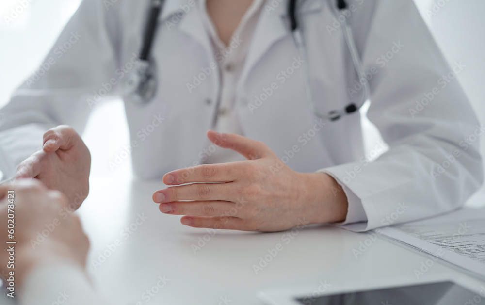 Doctor and patient sitting at the table in clinic office. The focus is on female physician's hands reassuring woman, only hands close up. Medicine concept Doctor and patient sitting at the table in clinic office. The focus is on female physician's hands reassuring woman, only hands close up. Medicine concept
