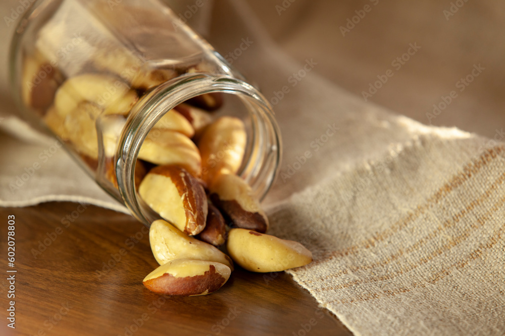Brazil nuts pouring out of the jar onto the table. Selective focus.