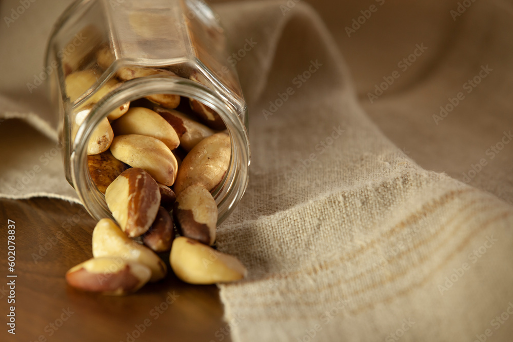 Brazil nuts pouring out of the jar onto the table. Selective focus.