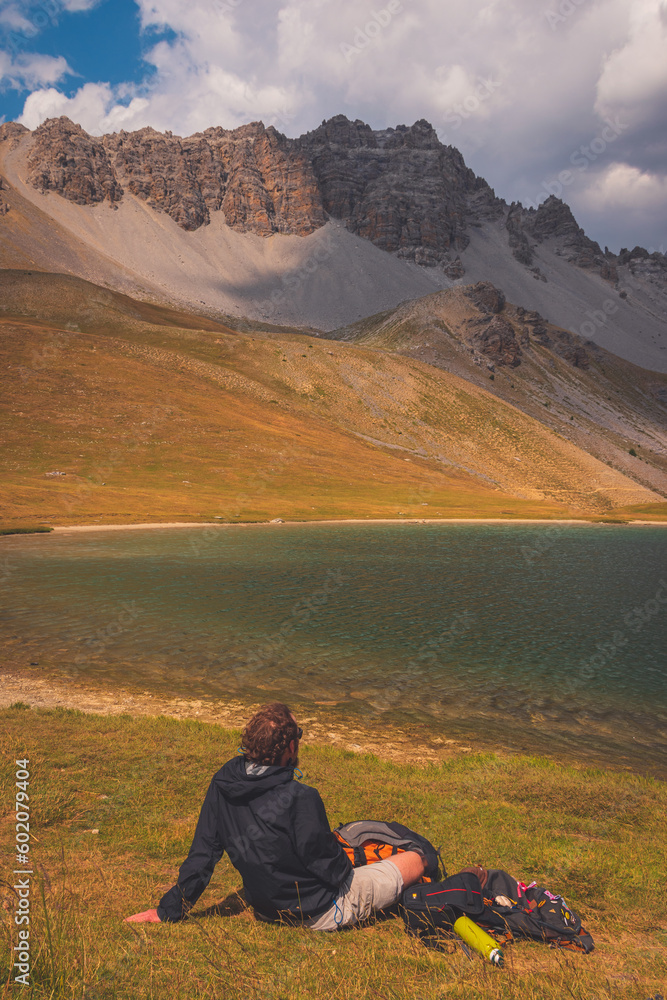 A male hiker sitting next to a mountain lake, Lac de Soulier (Hautes-Alpes)