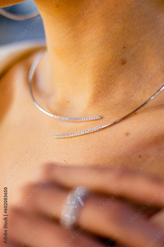 Closeup of a necklace with diamonds, diamonds, and white gold on the delicate neck of a girl. Woman srands in jewerly store. Closeup of a necklace with diamonds, diamonds, and white gold on the delicate neck of a girl. Woman srands in jewerly store.