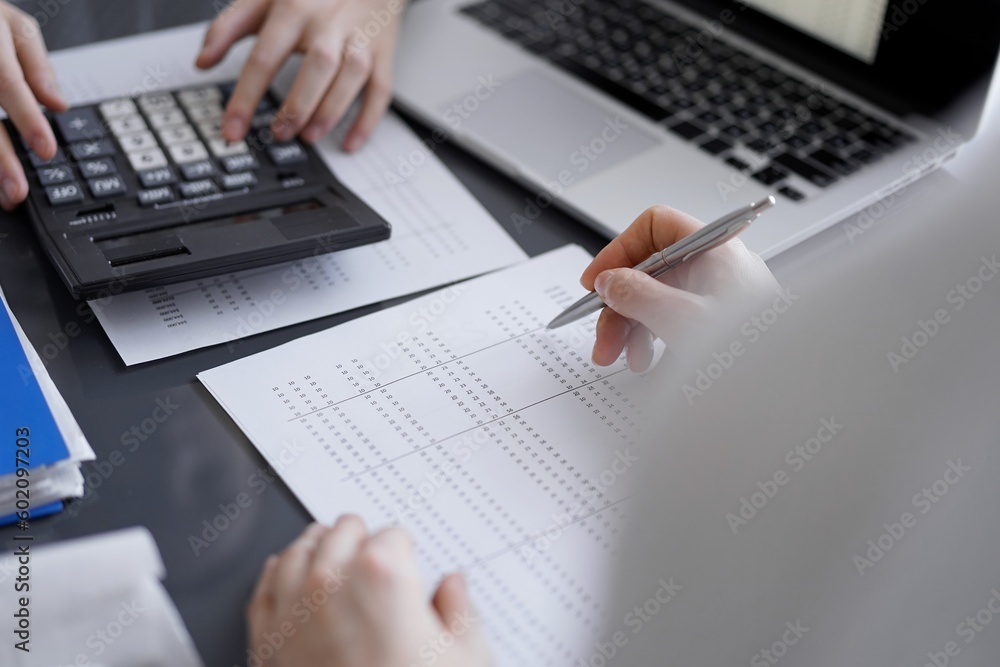 Woman accountant using a calculator and laptop computer while counting taxes for a client. Business audit concepts Woman accountant using a calculator and laptop computer while counting taxes for a client. Business audit concepts