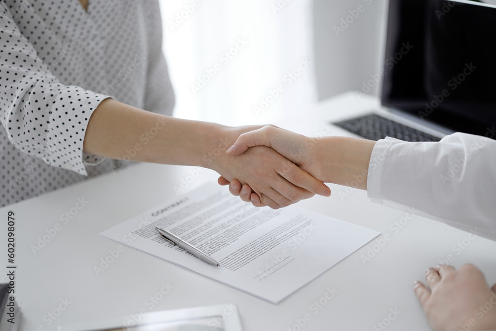 Business people shaking hands above contract papers just signed on the white table, closeup. Lawyers at meeting. Teamwork, partnership, success concept