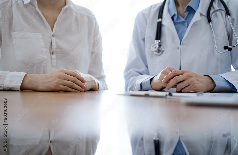 Doctor and patient discussing something while sitting near each other at the wooden desk in clinic, view from above. Medicine concept Doctor and patient discussing something while sitting near each other at the wooden desk in clinic, view from above. Medicine concept