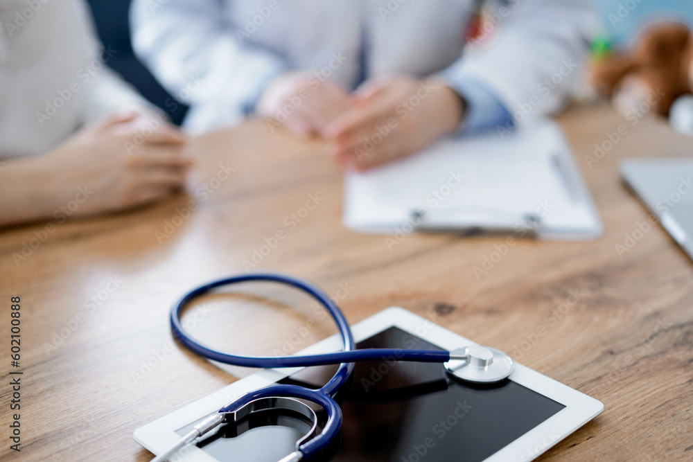 Doctor and patient discussing something while sitting near each other at the wooden desk in clinic, view from above. Medicine concept Doctor and patient discussing something while sitting near each other at the wooden desk in clinic, view from above. Medicine concept